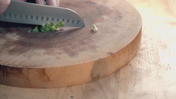 Slow Motion Slider Shot of Chefs Hands with Chef Knife Chopping Spring Onions on a Thick Wooden Chop