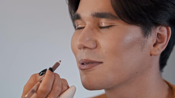 Make Up Artist Applying a Brown Pencil on the Lips of Male Model