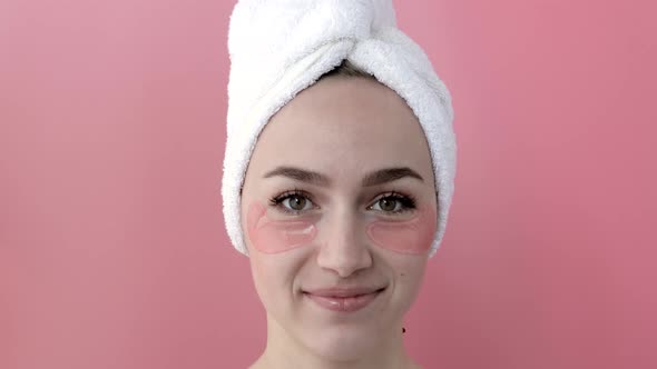 Plesant nude girl applying collagen eye masks on face in front of a mirror