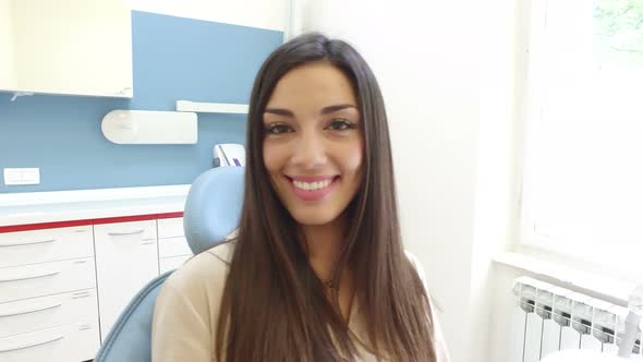 Close up of smiling woman looking at camera while sitting in the dental chair