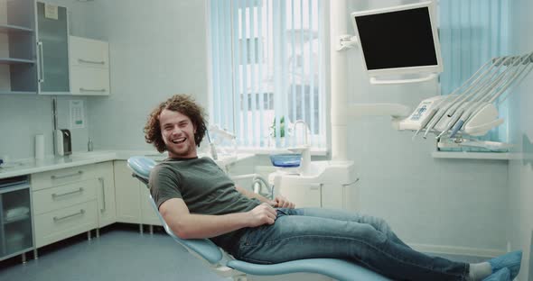 Charismatic Man with Curly Hair in Dentist Chair