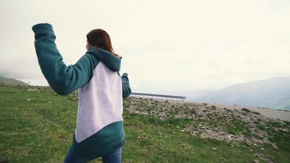 A Young Woman Hiker Running and Spinning on Top of a Mountain