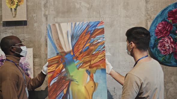 Gallery Workers Hanging Painting on Wall alt