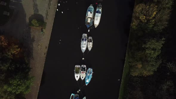 Descending shot over boats on canal, bird flies through right of shot