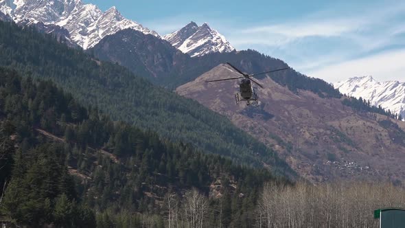 Helicopter Flying Above Lush Mountain Before Landing On The Ground