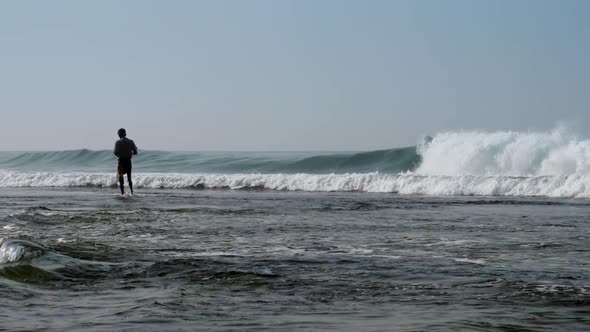 Local Fisherman Holds Rod in Hand in Waving Blue Ocean