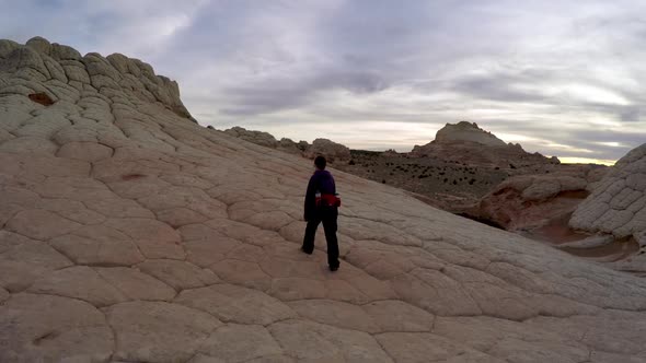 Following woman hiking in White Pocket