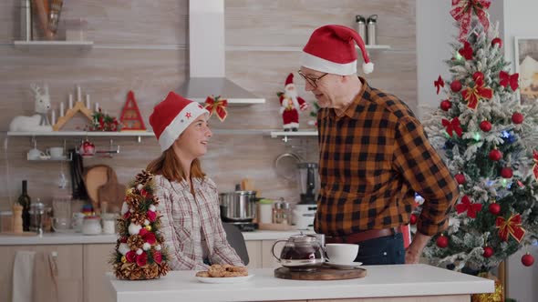 Grandfather Surprising Granddaughter with Wrapper Present Gift in Xmas Decorated Kitchen