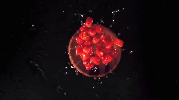 Super Slow Motion the Pieces of Chilli in a Wooden Plate with Splashes of Water