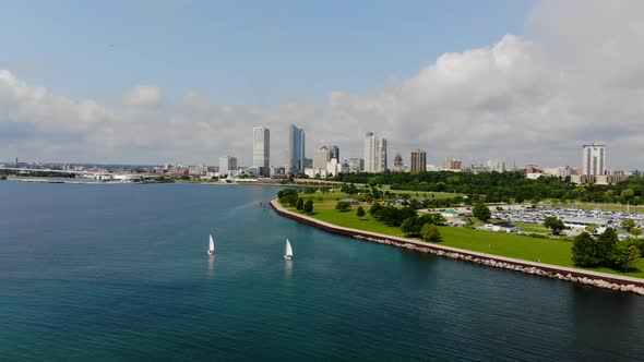 Slow aerial pan of sailboats in bay with city skyline in the background