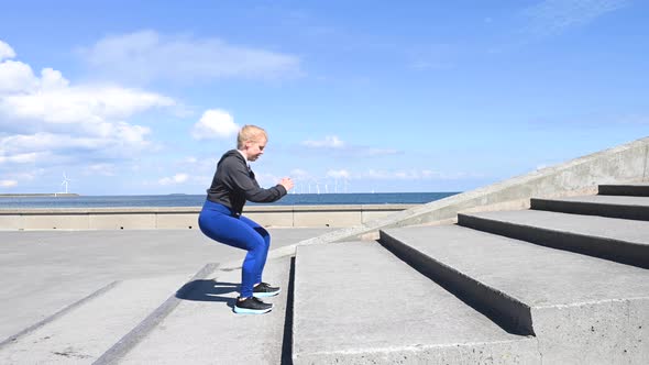 Attractive, fit, young woman doing jump exercises on stairs, in slow motion, stock footage