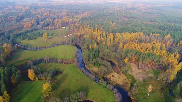 Aerial view of river crossing forest during Autumn, Estonia.