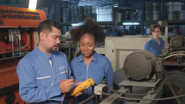 Two professional engineers inspect machines' electric systems at the factory.