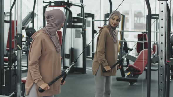 Woman in Hijab Exercising with Cable Machine in Gym