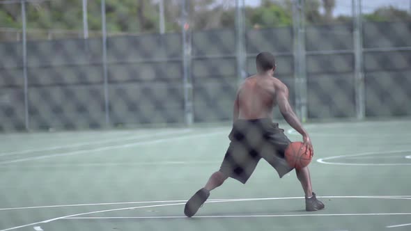 A young man playing basketball on a rainy day.