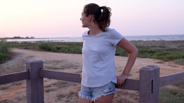 Teen girl standing on walkway by the sea and looking aside