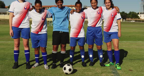 Female soccer team standing arm to arm on soccer field. 4k