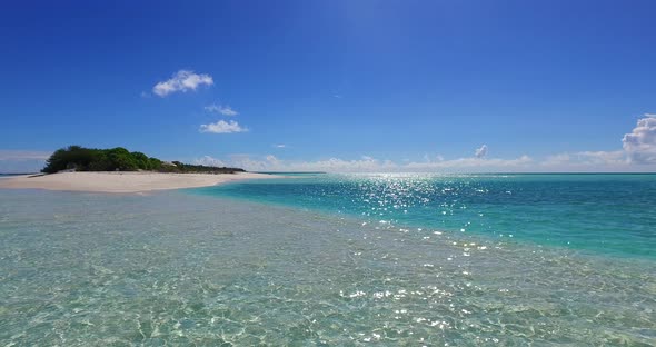 Wide flying island view of a white sand paradise beach and aqua turquoise water background in 4K