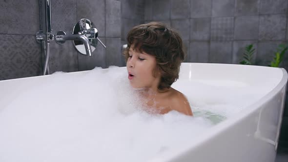 Smiling 5-Aged Nice Boy with Brown Hair Taking a Bath with Foam