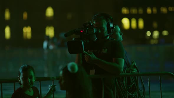 TV cameraman filming an event, at night