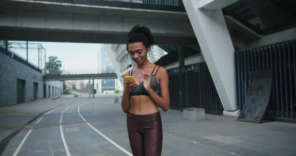 AfricanAmerican Lady in Tracksuit Texts Message on Phone