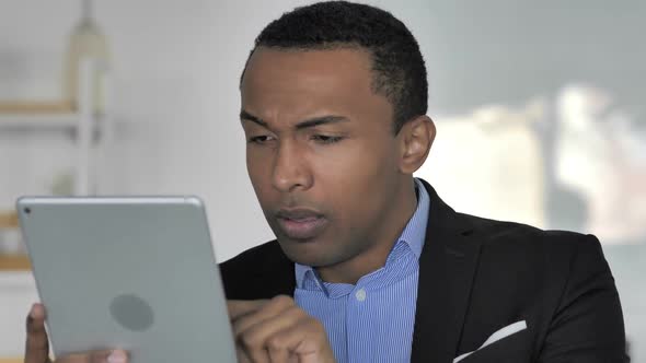 Close Up Of Casual AfroAmerican Businessman Upset By Loss While Using Tablet