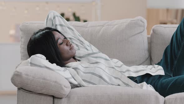 Young African American Woman Lies Relaxing on Comfortable Couch with Closed Eyes Attractive Girl