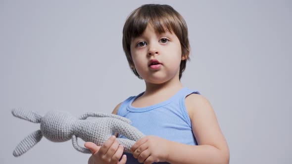 Child Is Sitting on the Bed in a T-shirt and Playing