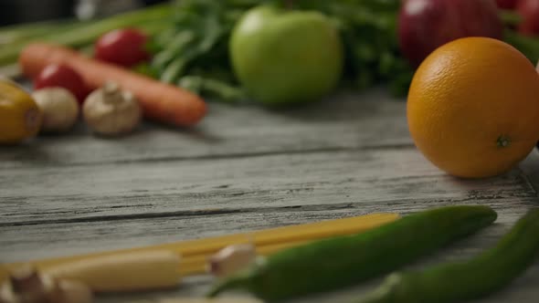 Crop Person Rolling Orange on Wooden Rustic Table. Vegetarian Food Concept.