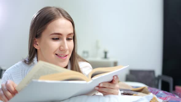 Beautiful Young European Woman Enjoying Weekend Reading Interesting Book at Home