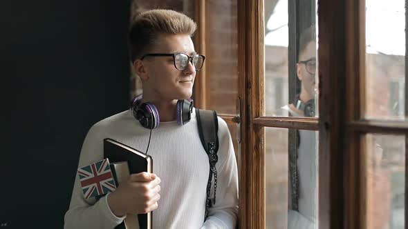 Student Holding Great Britain's Flag and Standing By the Window