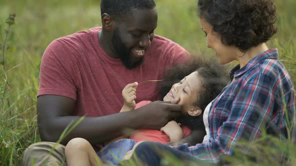 Delighted father holding his little daughter and playing with her curly hair