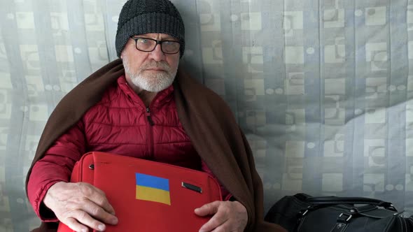 Portrait of a Sad Elderly Ukrainian Refugee Sitting on the Floor in a Resettlement Center