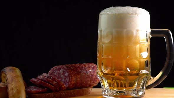 Pouring beer into the glass. Sausage with mug cold craft beer in a glass with water drops