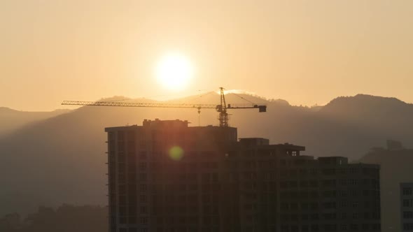 Sunrise Over a Tower Crane on Construction Site with a Skyscraper in the City. Timelapse.