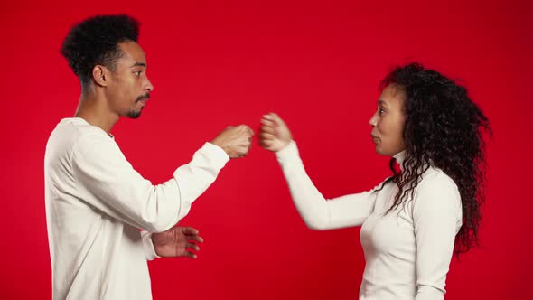 African Couple Doing Funny Greeting As in Old Films with Hand Gestures on Red