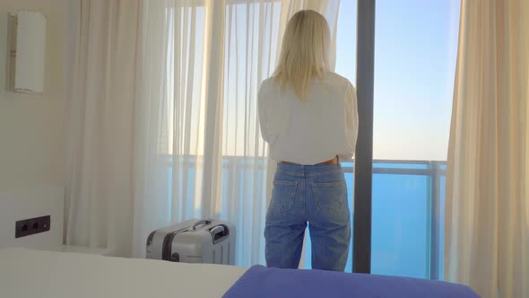 Portrait of tourist visiting hotel, standing at window and admiring beautiful