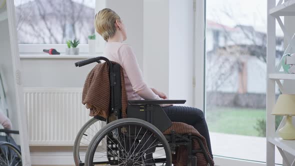 Side View of Joyful Disabled Woman in Wheelchair at Home Waving To Neighbors