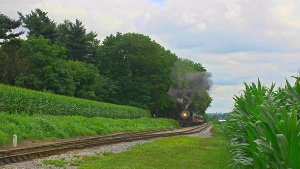 Front View of an Antique  Steam Passenger Train Approaching Traveling Thru Farmlands and Corn Fields