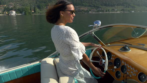 A woman on a classic luxury wooden runabout boat on an Italian lake