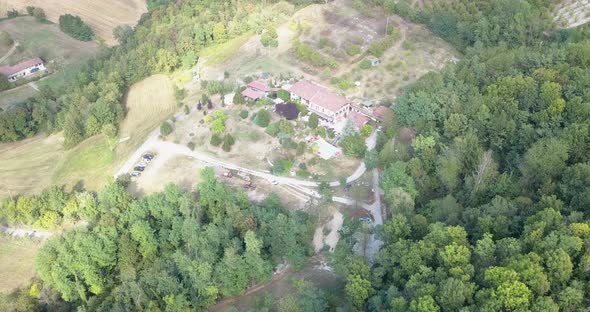 Hilly forest in the italian countryside with a vacation house underneath and roads.