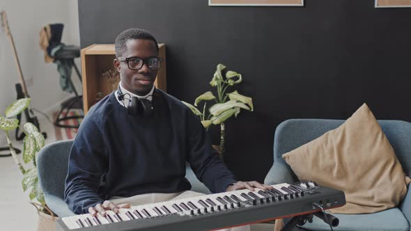 Man Posing with Synthesizer at Home