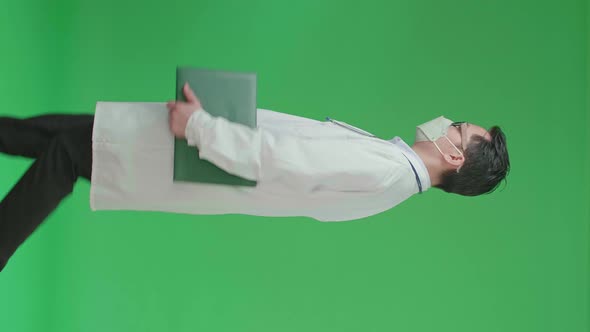 Asian Doctor With Stethoscope Wearing Mask, Holding Document File While walking On Green Screen