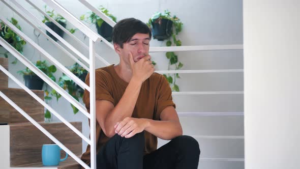 Pensive Sad and Depressed Young Man Sitting Alone on Stairs at Home Painful Sad Man