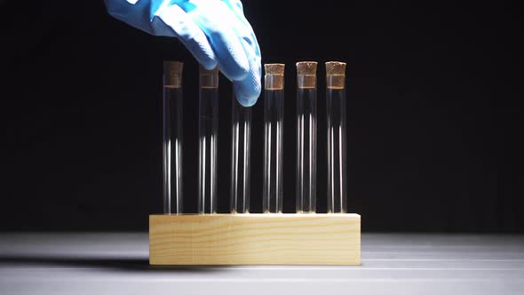 Close-up of a Gloved Hand Pulls a Test Tube From the Stand alt
