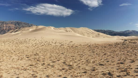 Drone Flying Low Above Desert with Dune Hill in Background