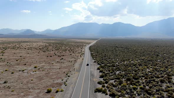 Aerial View of Car Driving on Asphalt Road in the Middle of Dusty Dry Desert Land