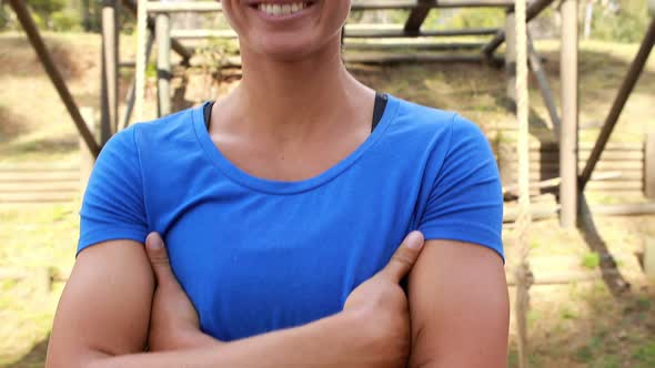 Smiling fit woman standing with arms crossed in park