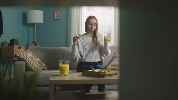 Young Girl on a Beige Sofa Holding Pizza and Juice