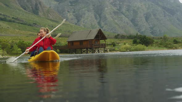 Caucasian couple having a good time on a trip to the mountains, kayaking together on a lake